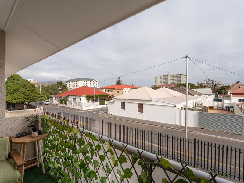 A covered balcony overlooking a suburban street with residential properties and clear neighborhood views.
