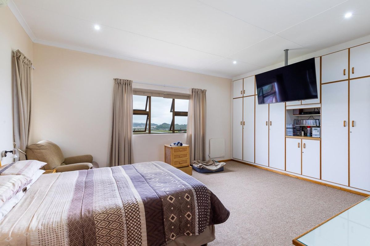 Spacious bedroom featuring extensive built-in cabinetry, recessed ceiling lighting, and large windows offering scenic views.