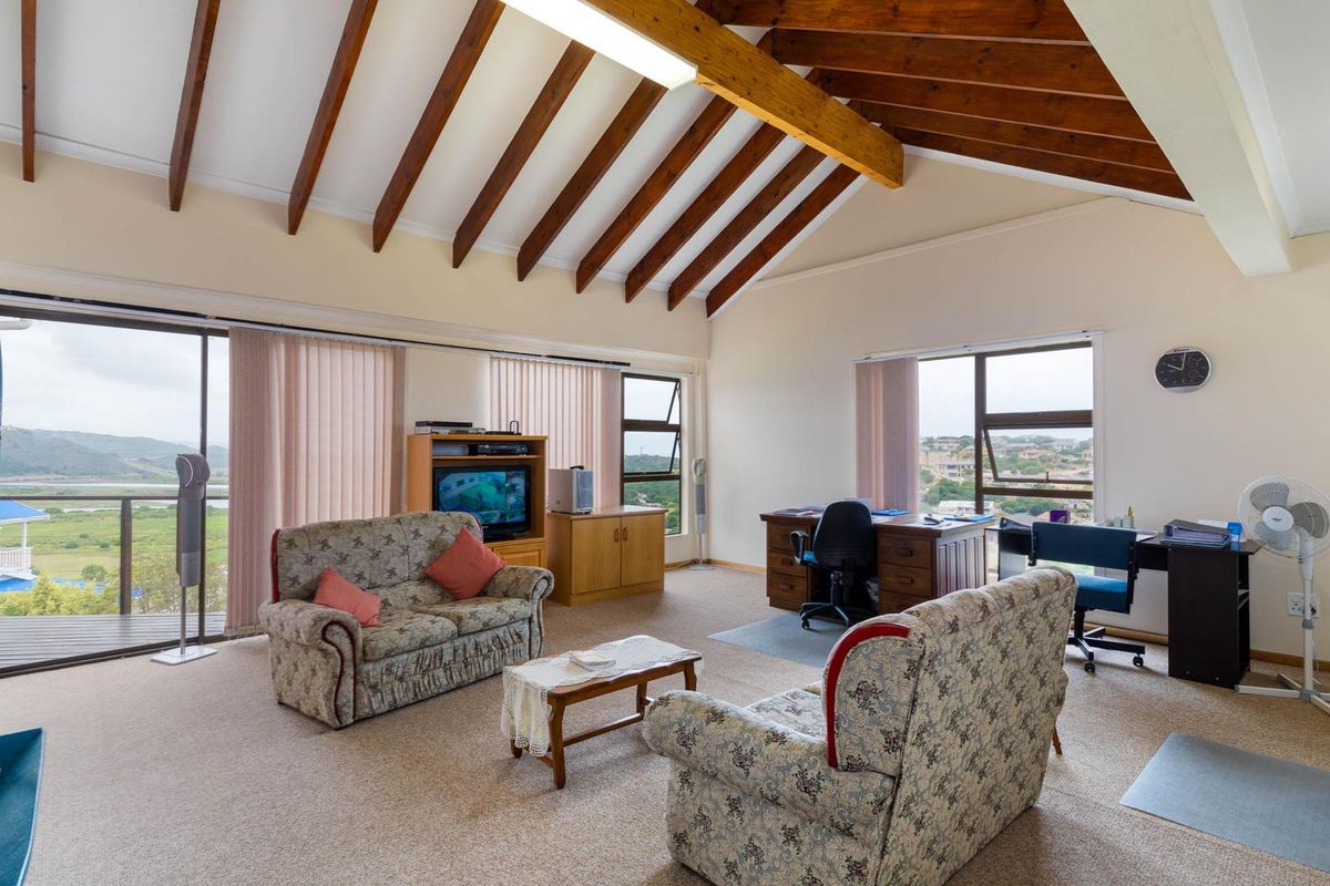 Spacious living area featuring high vaulted timber-beamed ceilings, large windows with scenic views, and direct access to an outdoor balcony.