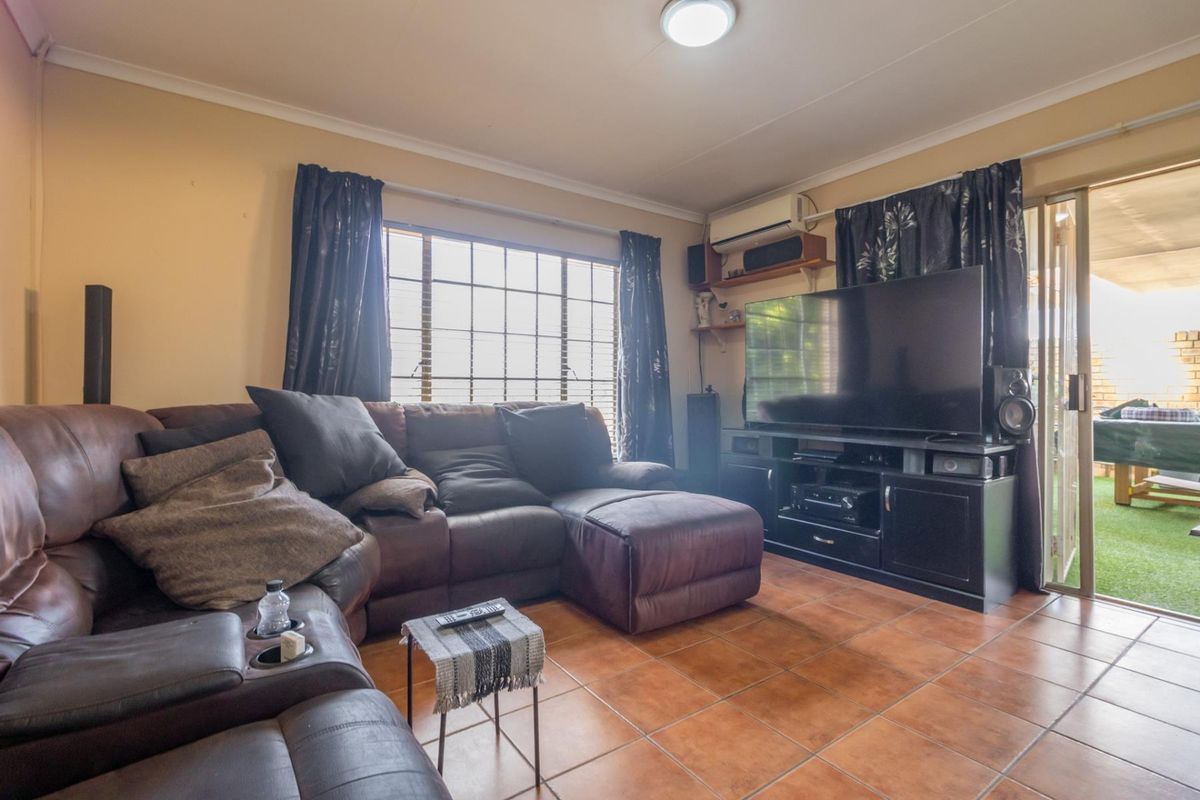 A living room featuring tiled flooring, an air conditioning unit, and a sliding glass door providing access to an outdoor area.