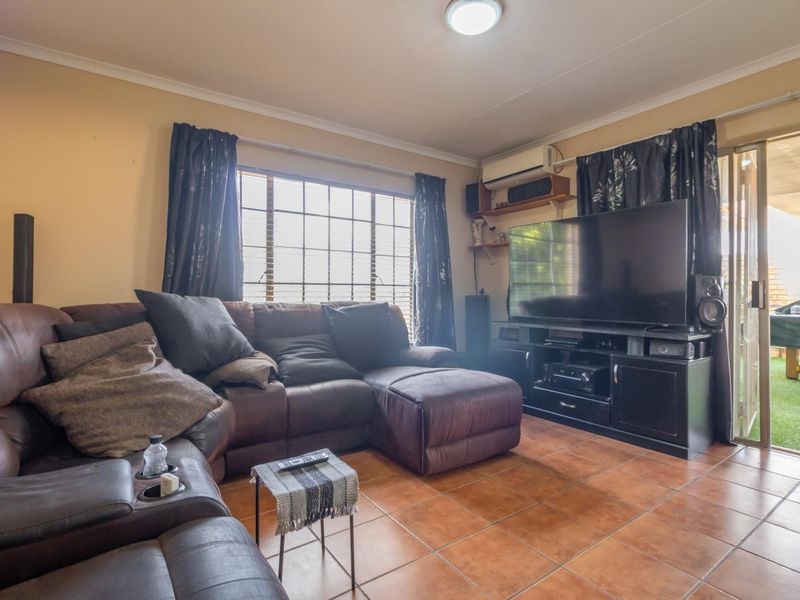 A living room featuring tiled flooring, an air conditioning unit, and a sliding glass door providing access to an outdoor area.
