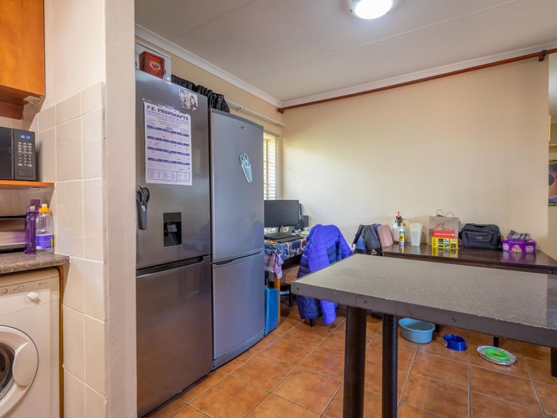 A functional kitchen area featuring tiled flooring, built-in cabinetry, and integrated appliance space, providing a practical layout for daily culinary and utility tasks.