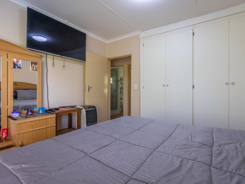 A functional bedroom featuring built-in cupboards and direct access to an en-suite bathroom.