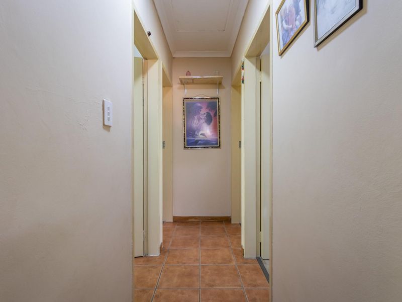 A functional interior hallway featuring tiled flooring and multiple doorways leading to adjacent rooms.