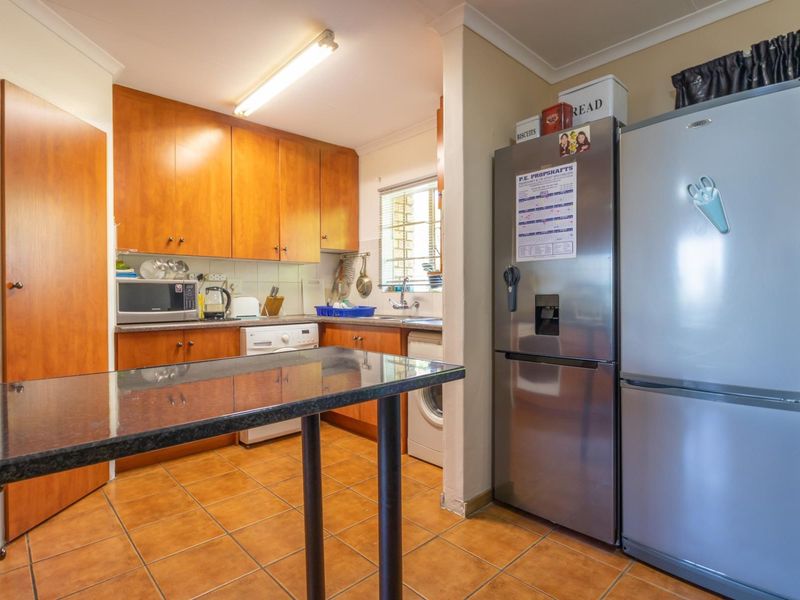 Functional kitchen featuring wood-finish cabinetry, granite countertops, tiled flooring, and a convenient breakfast bar, providing a practical workspace for daily meal preparation.