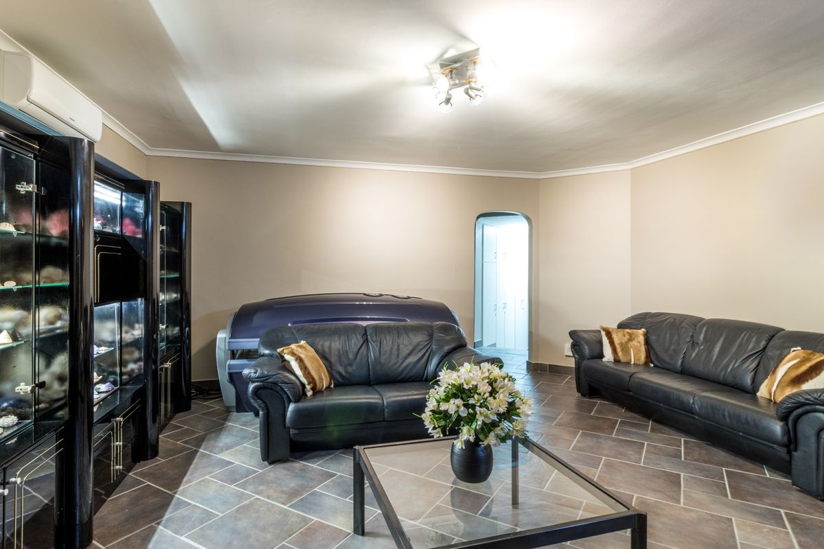 A multi-purpose living space featuring tiled flooring, a wall-mounted air conditioning unit, and an arched doorway leading to an adjacent room.
