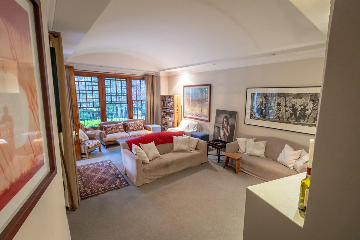Spacious living room featuring a unique vaulted ceiling, large multi-pane windows, and neutral carpeting, offering a comfortable and well-lit area for relaxation.
