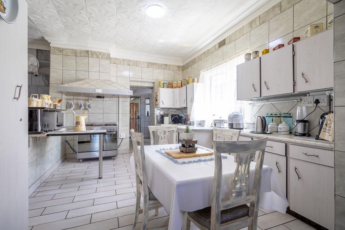 A functional kitchen featuring tiled walls, built-in cabinetry, a gas stove with extractor hood, and a dedicated dining area.