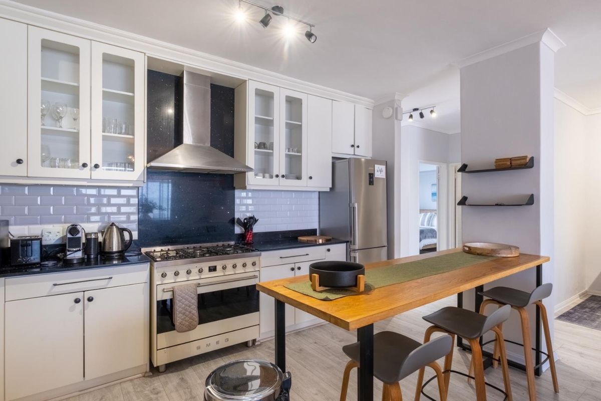 Modern kitchen featuring white cabinetry, subway tile backsplash, dark stone countertops, and a stainless steel gas range with extractor fan.