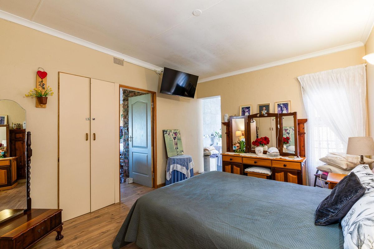 A bedroom featuring built-in cupboards, laminate flooring, and access to an adjoining room, providing a functional and lived-in space.