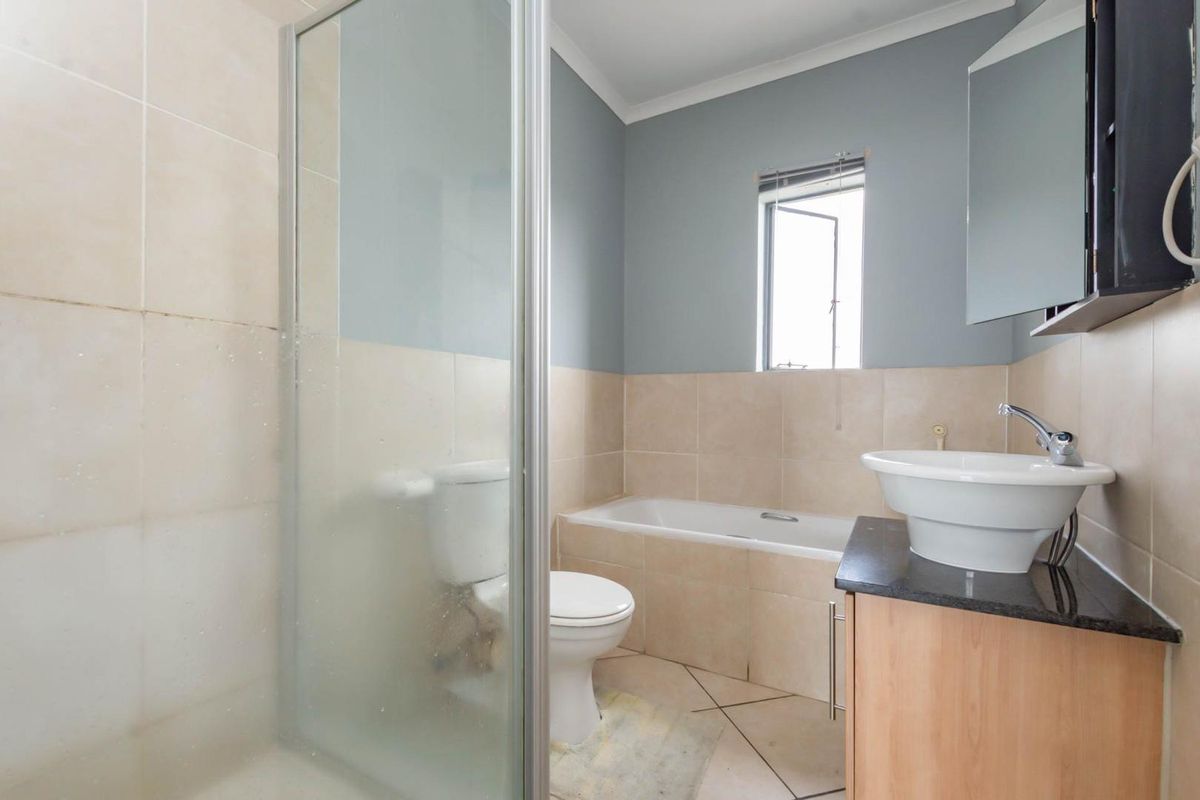 A functional bathroom featuring a tiled shower enclosure, a built-in bathtub, a vanity with a vessel sink, and a toilet.