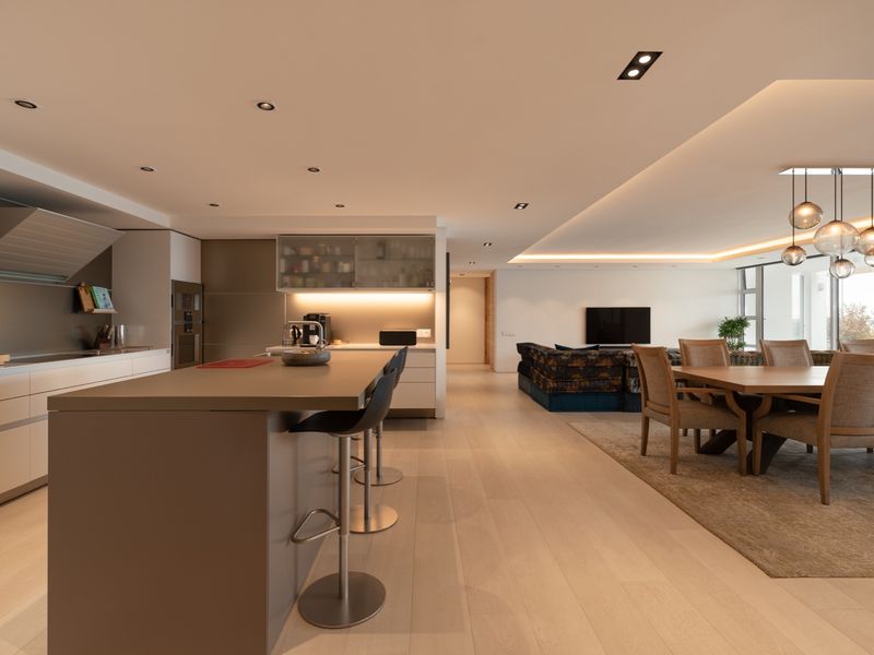 Spacious open-plan living area featuring a modern kitchen with a central island, integrated appliances, recessed lighting, and seamless flow to the dining and lounge space.