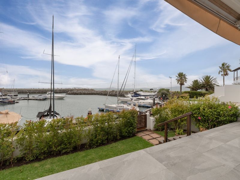 A private patio area featuring stone tiling and a retractable awning, offering direct views over the marina and boat moorings.