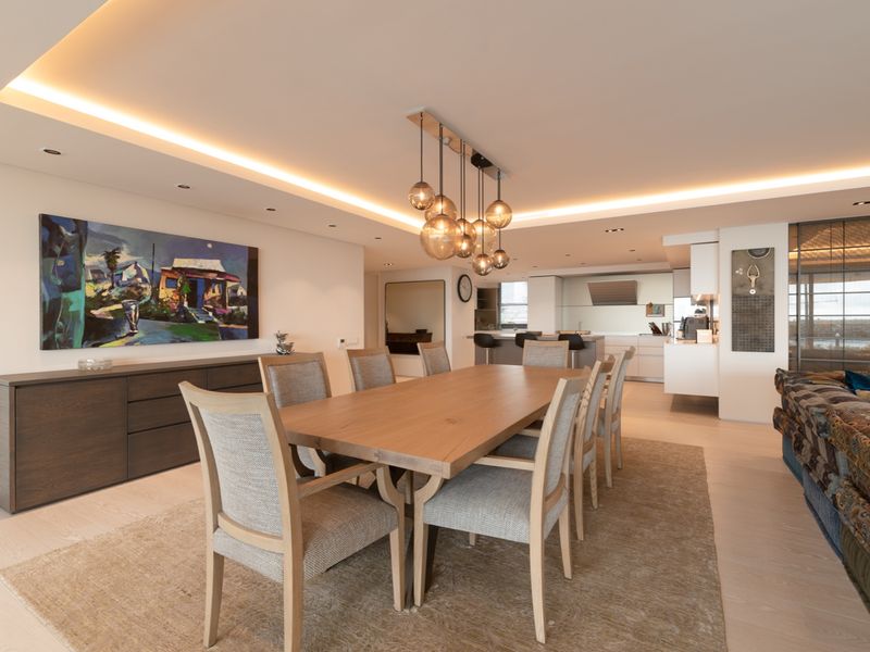 Spacious open-plan dining and kitchen area featuring recessed ceiling lighting, modern cabinetry, and high-quality finishes throughout this contemporary apartment.