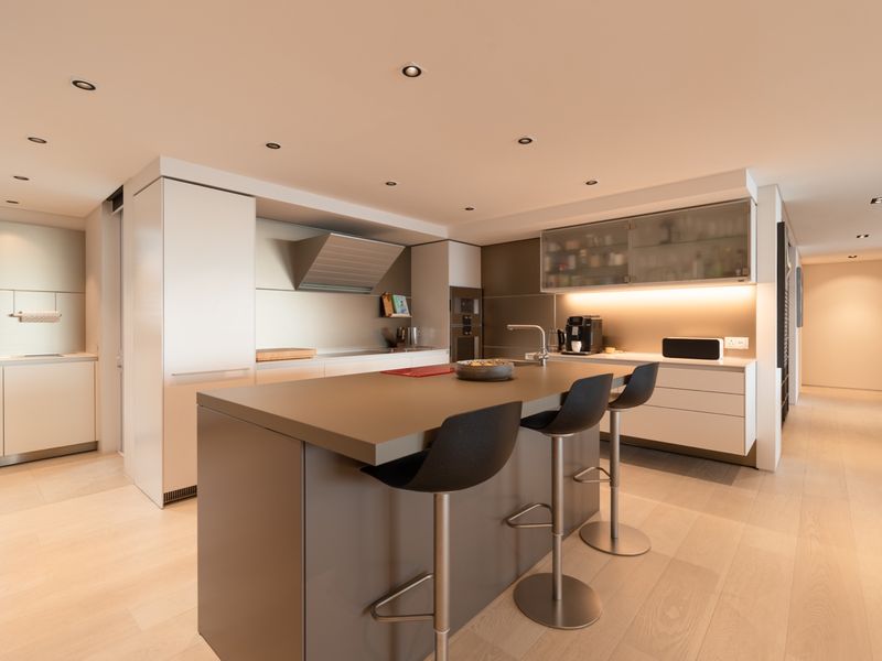 Modern open-plan kitchen featuring a central island with breakfast bar, integrated cabinetry, built-in oven, extractor fan, and recessed ceiling lighting.
