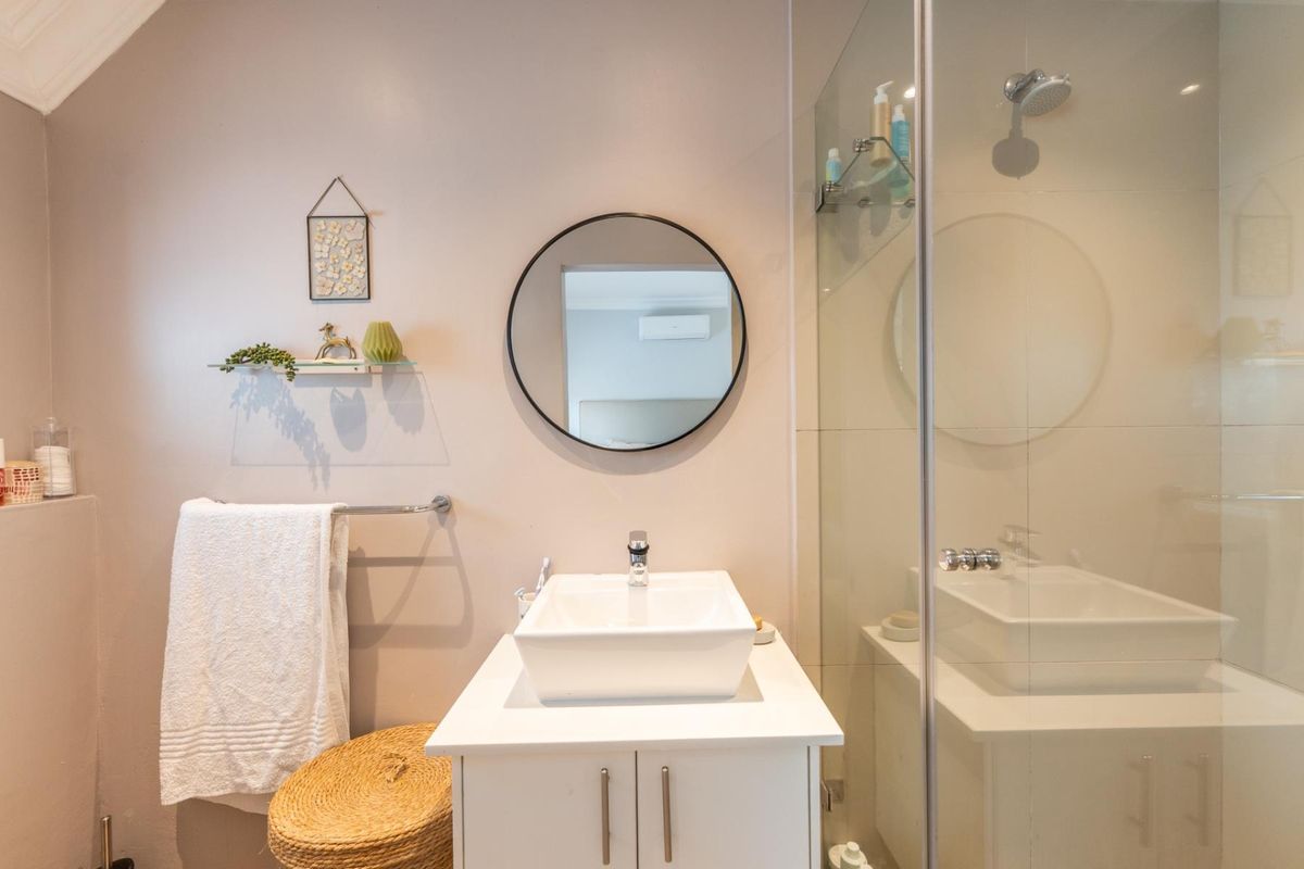 Modern bathroom featuring a contemporary vessel sink vanity, a glass-enclosed shower, and a circular wall mirror.