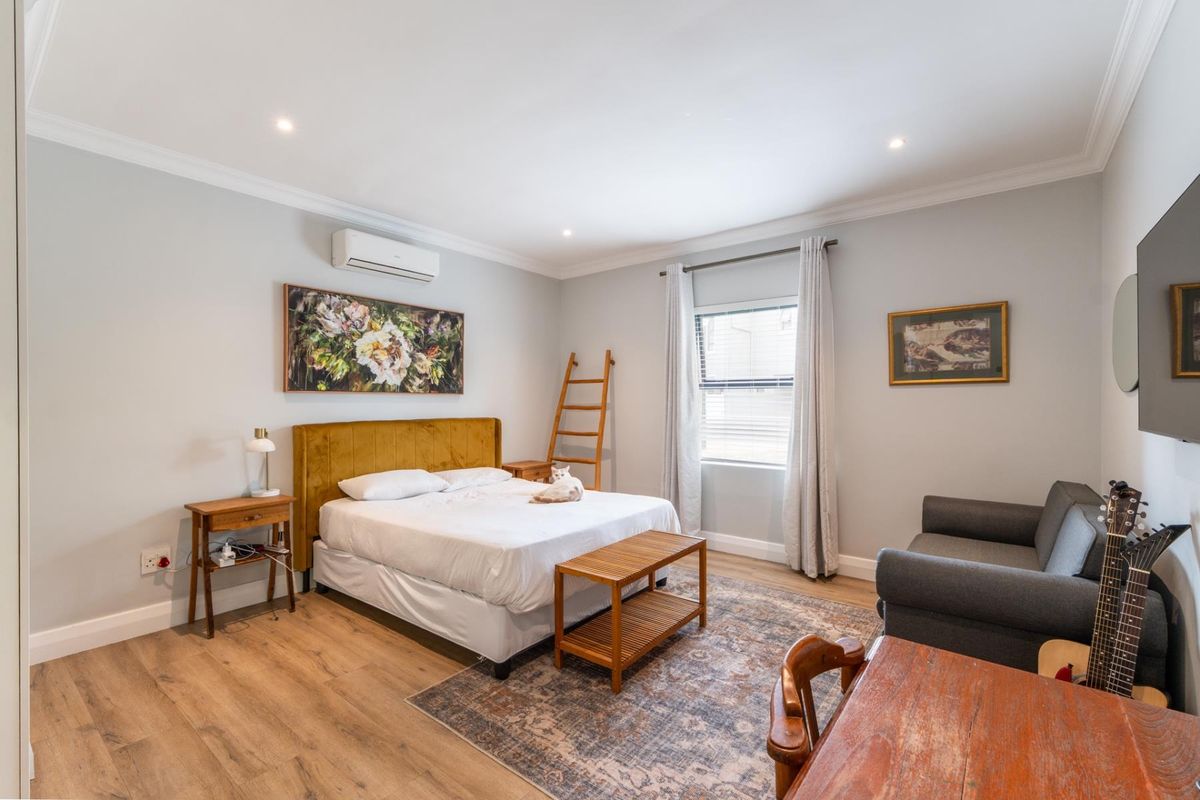 A well-maintained bedroom featuring wood-look flooring, recessed ceiling lighting, and a wall-mounted air conditioning unit.