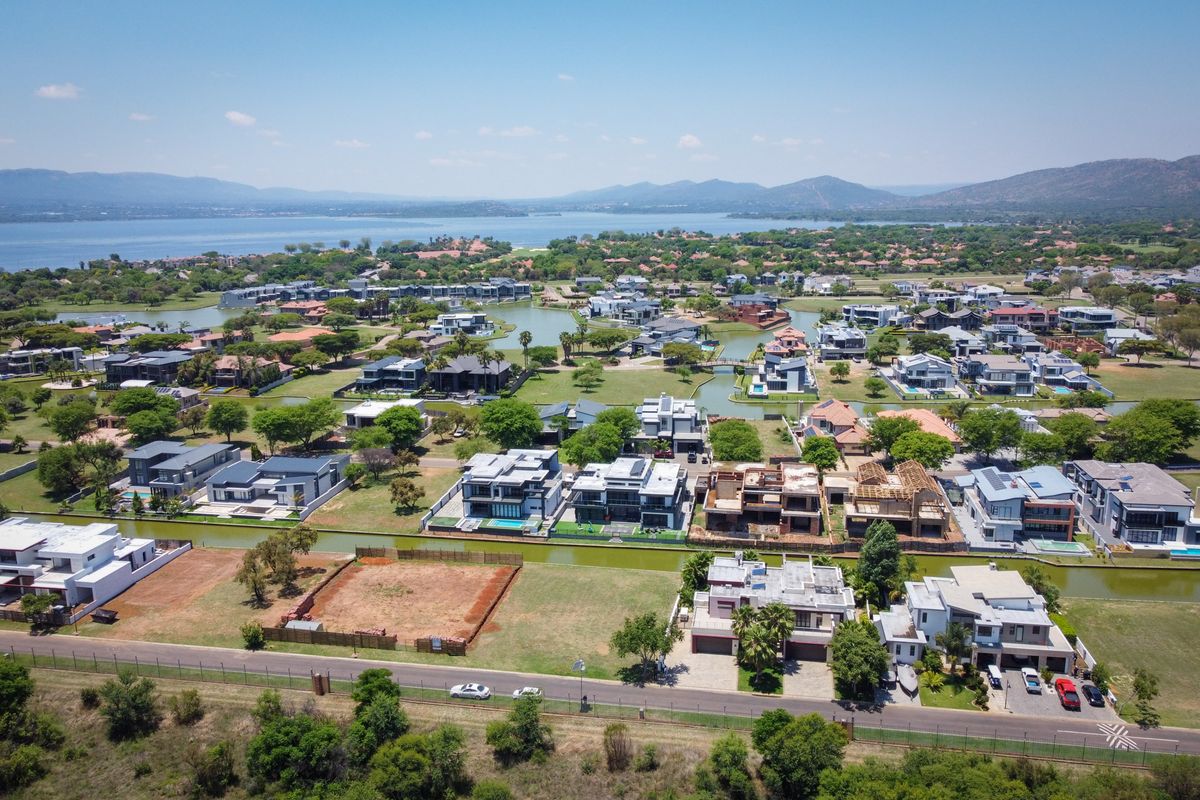 Aerial view of a residential estate featuring vacant land plots, waterfront properties, and established luxury homes with scenic lake and mountain views.