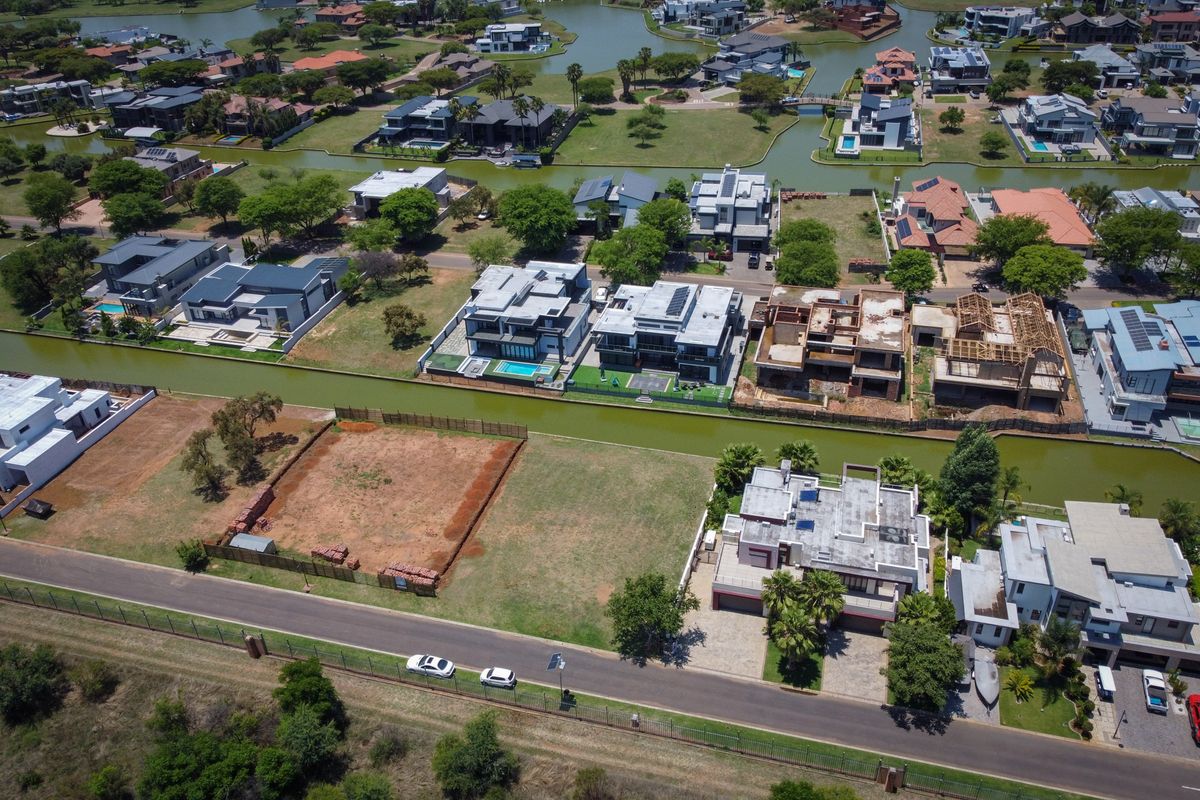 Aerial view of a vacant residential plot in a waterfront estate, featuring established surrounding infrastructure and canal access.