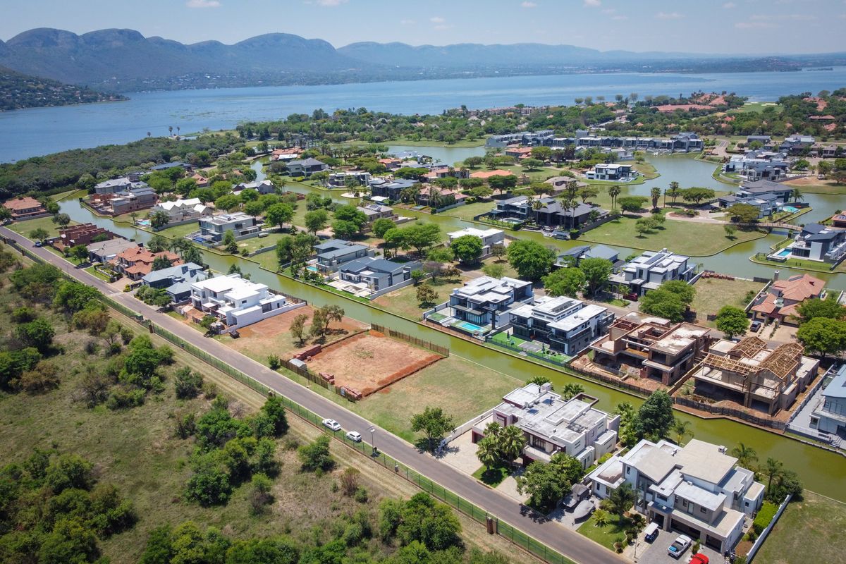 Aerial view of a residential estate featuring vacant land plots, waterfront access, and established modern homes with mountain and lake views.