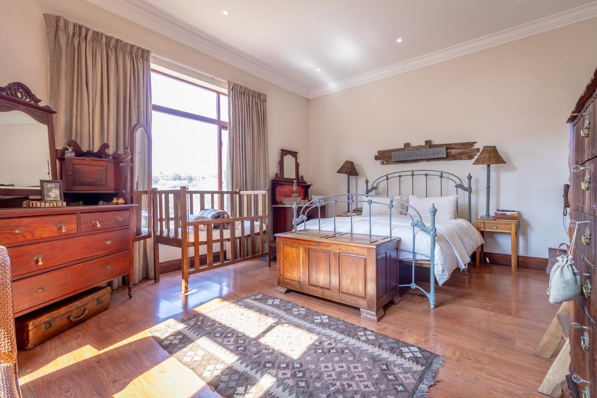 Spacious bedroom featuring warm-toned laminate flooring, large window with natural light, recessed ceiling lighting, and classic crown molding.