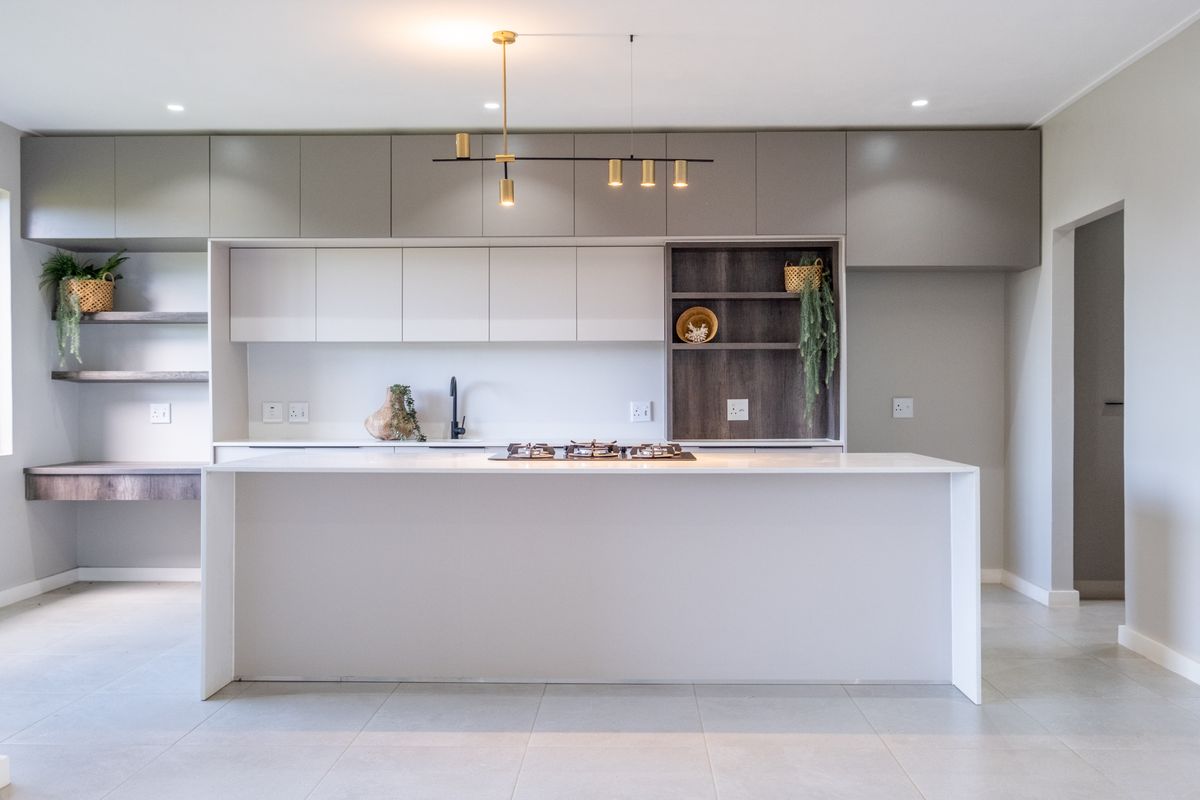 Modern kitchen featuring a central island with a built-in gas hob, sleek cabinetry, and integrated shelving, finished with high-quality fixtures and neutral tones.