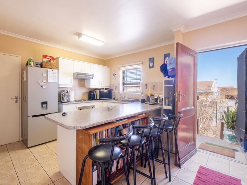 Functional kitchen featuring white cabinetry, laminate countertops with a breakfast bar, tiled flooring, and direct access to an outdoor area.