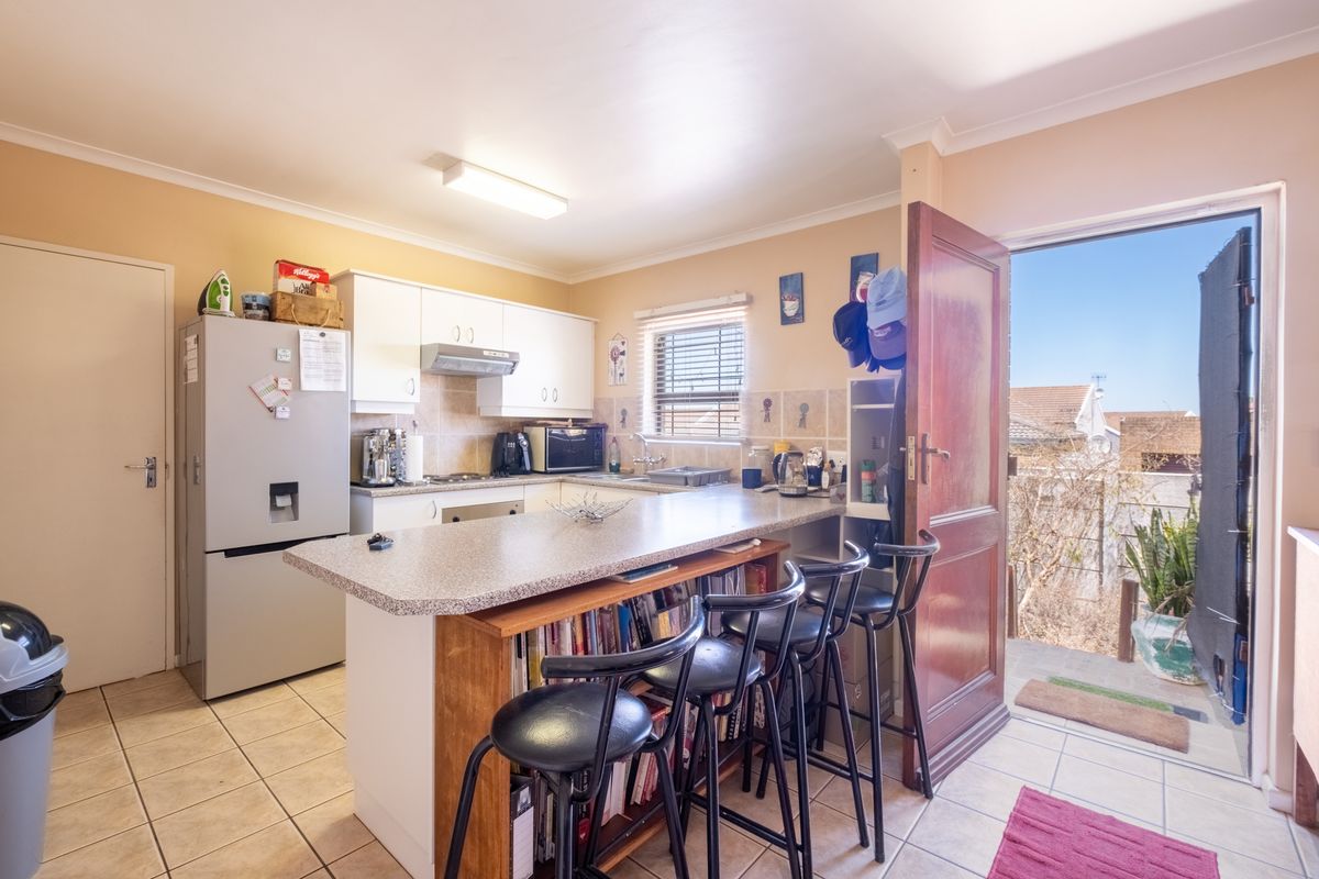 Functional kitchen featuring white cabinetry, laminate countertops with a breakfast bar, tiled flooring, and direct access to an outdoor area.
