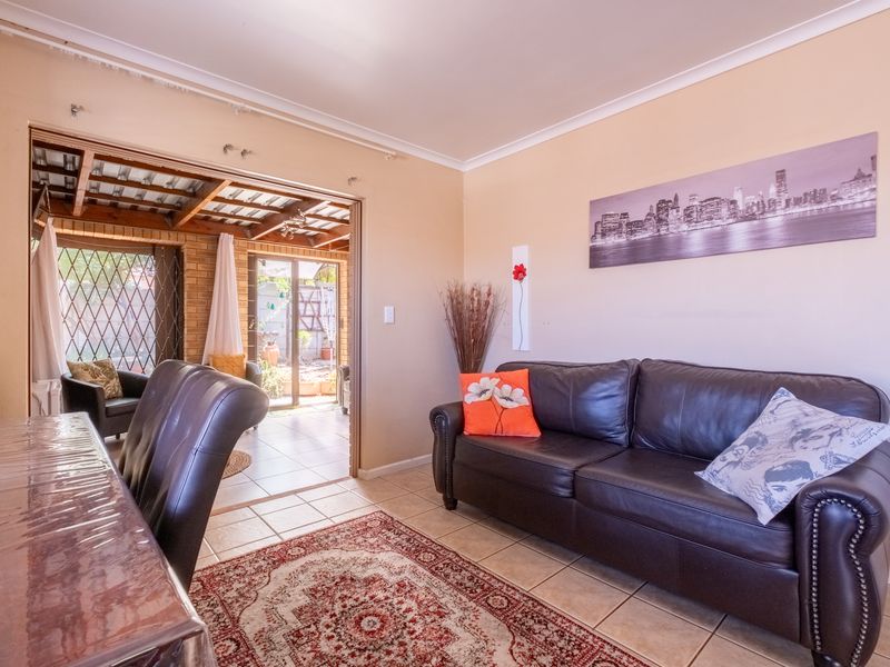 A living room featuring tiled flooring and a sliding glass door providing access to an adjoining covered patio area.