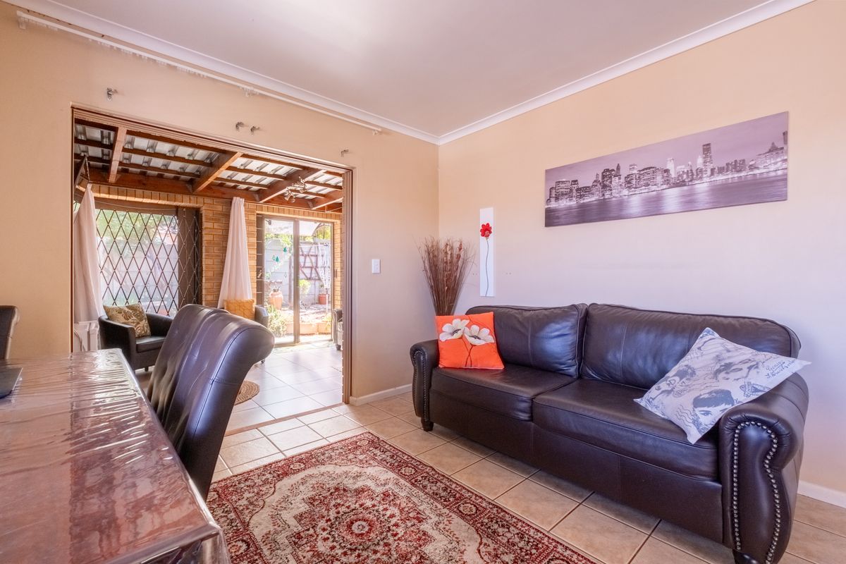 A living room featuring tiled flooring and a sliding glass door providing access to an adjoining covered patio area.