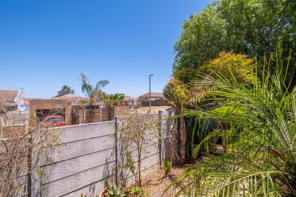 A view of the rear garden area featuring a precast concrete boundary wall and established trees, offering a private outdoor space.