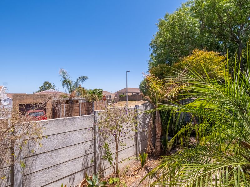 A view of the rear garden area featuring a precast concrete boundary wall and established trees, offering a private outdoor space.