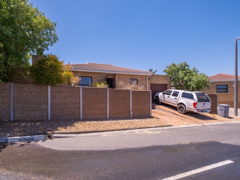 Front exterior view of a brick townhouse featuring a tiled roof, private driveway, and precast concrete boundary wall.
