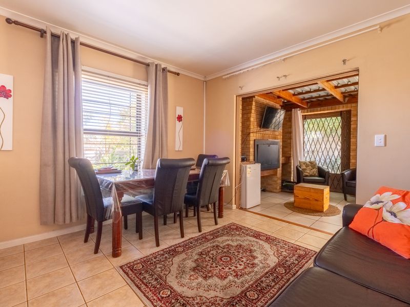 Open plan living and dining area featuring tiled floors, a brick fireplace, and direct access to a covered patio space.