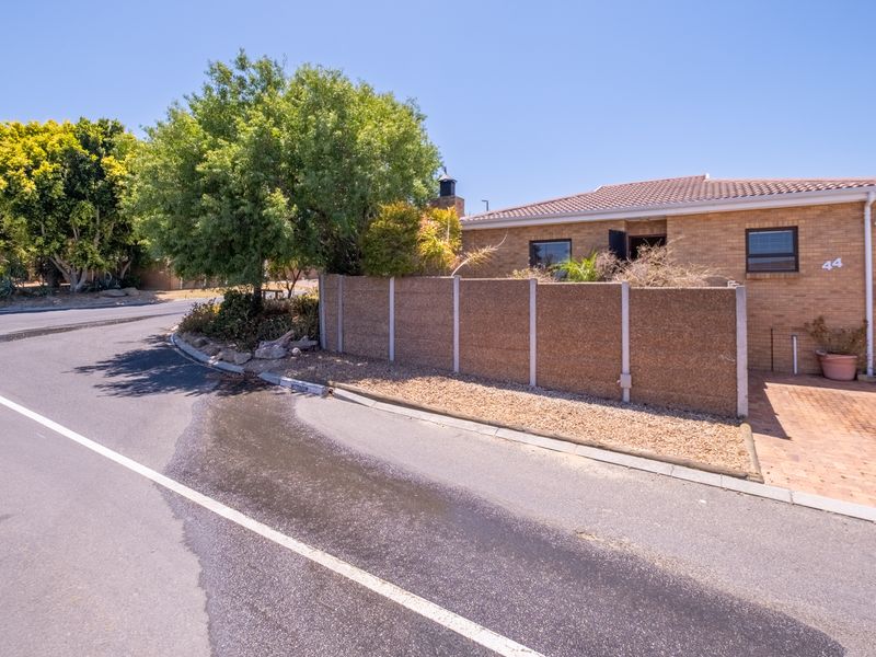 Front exterior view of a brick townhouse featuring a tiled roof, paved driveway, and a private boundary wall.
