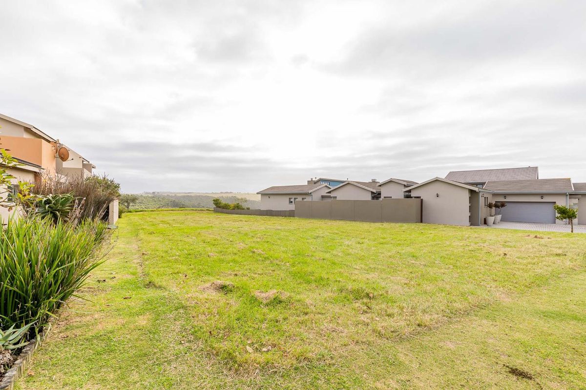 A vacant residential plot featuring established grass, clear boundaries, and surrounding residential development, offering a prime opportunity for new construction.