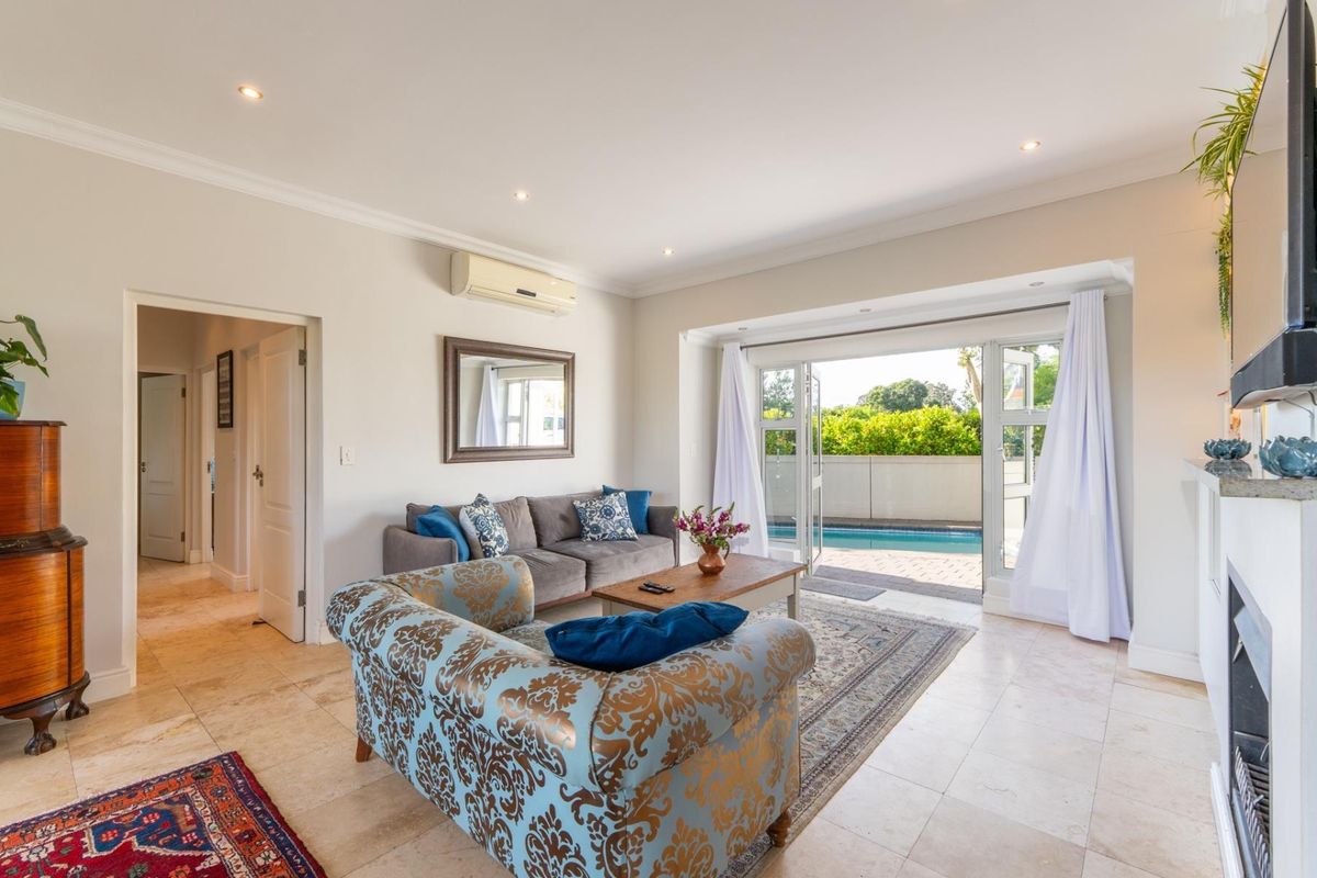 Bright living room featuring tiled flooring, recessed lighting, and double doors opening directly onto a private swimming pool area.