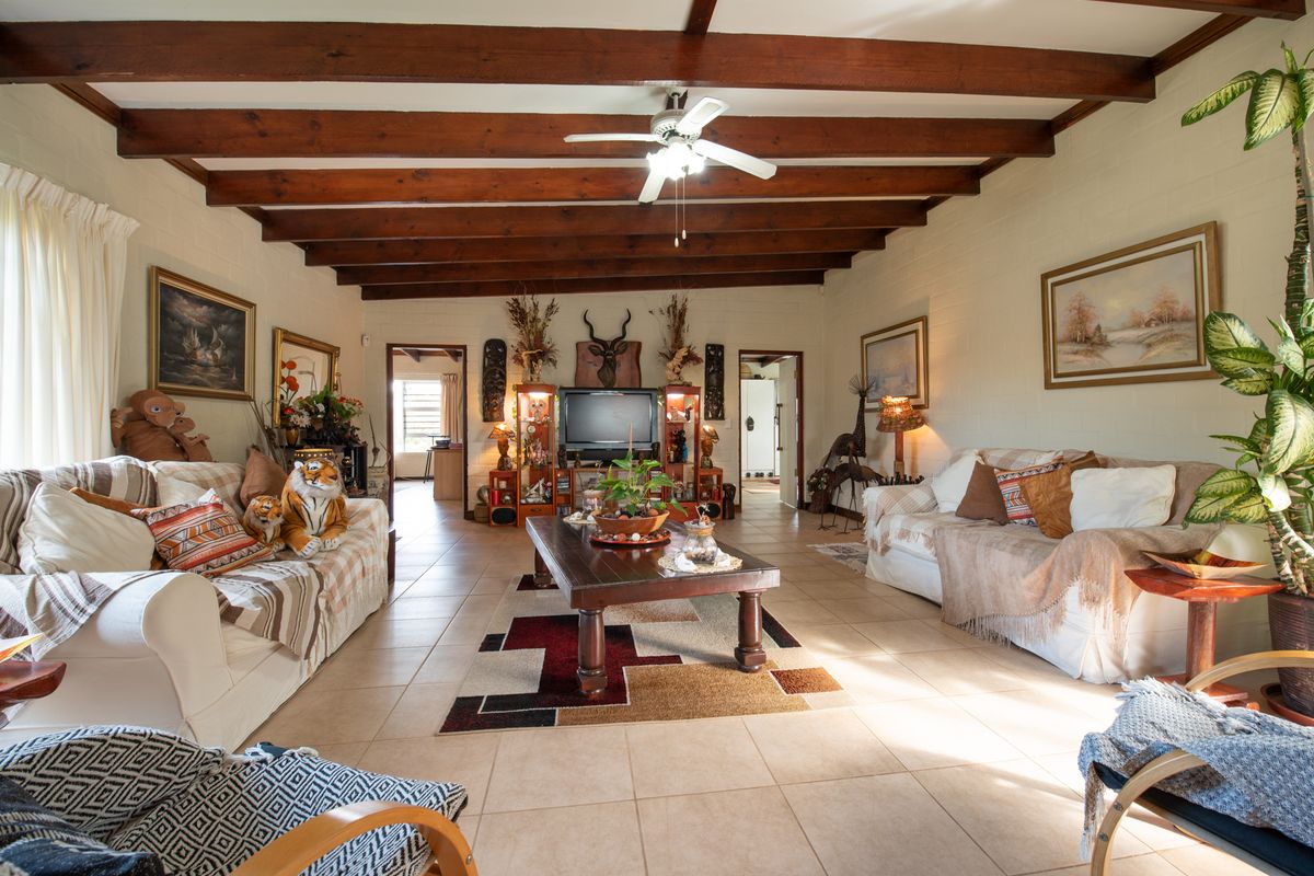 Spacious living room featuring exposed timber ceiling beams, tiled flooring, and a neutral color palette, offering a warm and inviting atmosphere.