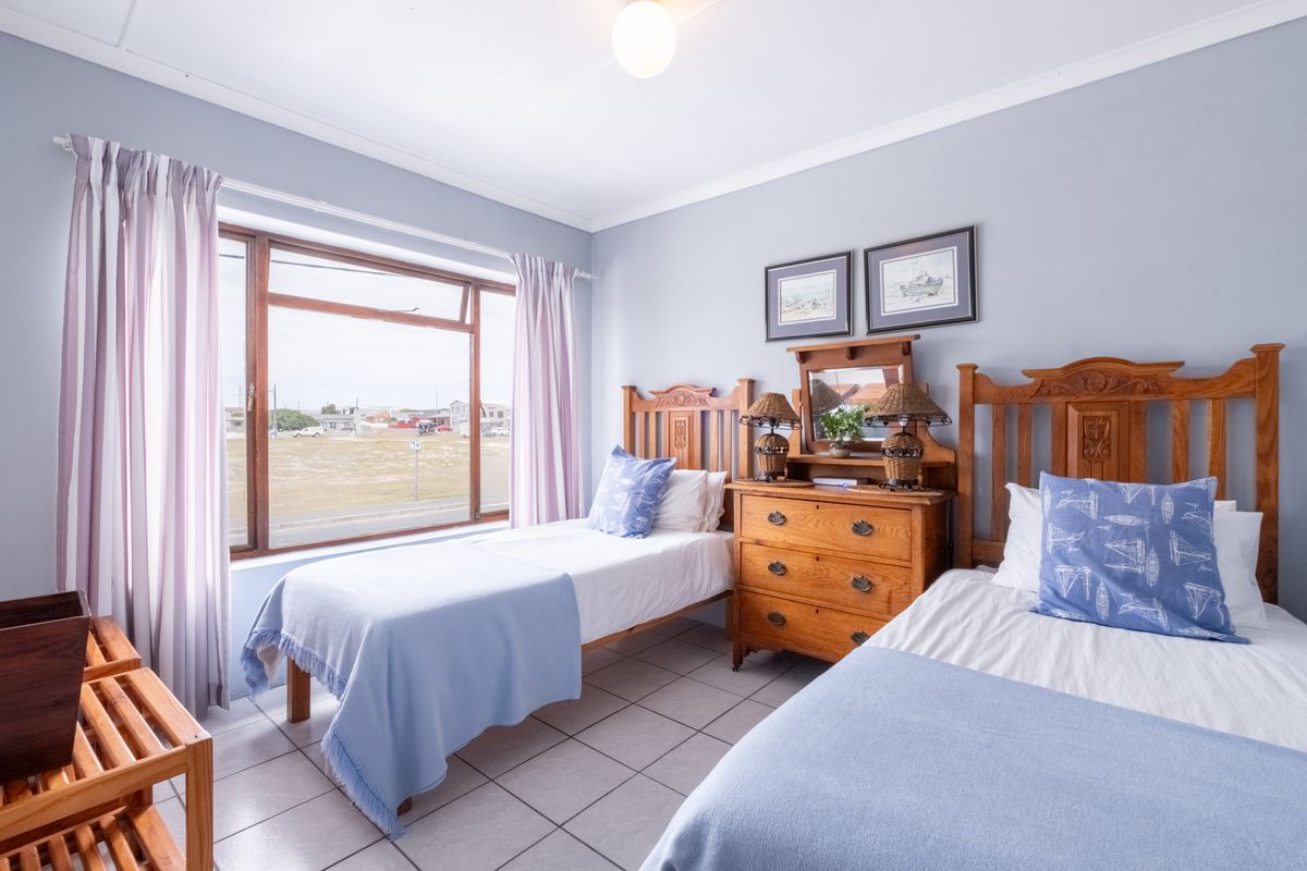 A bright bedroom featuring tiled flooring, large window with natural light, and neutral wall finishes.