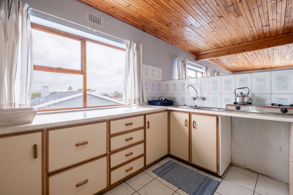 A dated kitchen featuring wooden ceiling paneling, tiled splashbacks, and laminate countertops with built-in cabinetry and a double sink.