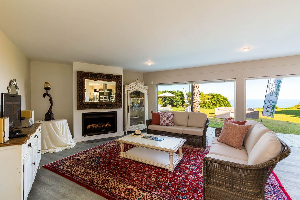 Spacious living room featuring a built-in fireplace, recessed lighting, and large sliding glass doors that open to a scenic garden and ocean view.
