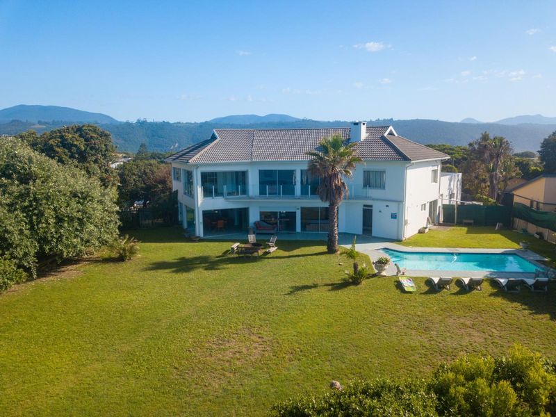 Aerial view of a large two-story residential property featuring a spacious rear garden, a swimming pool, and a balcony overlooking the landscape.