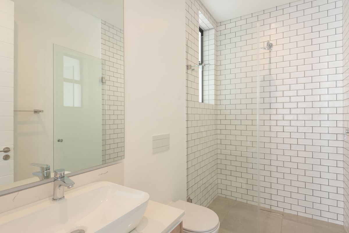 Modern bathroom featuring a glass-enclosed walk-in shower with white subway tiles, a contemporary vanity with a vessel sink, and a large wall-mounted mirror.