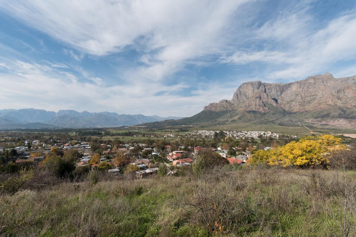 A scenic landscape view overlooking a residential valley with mountain ranges in the background.