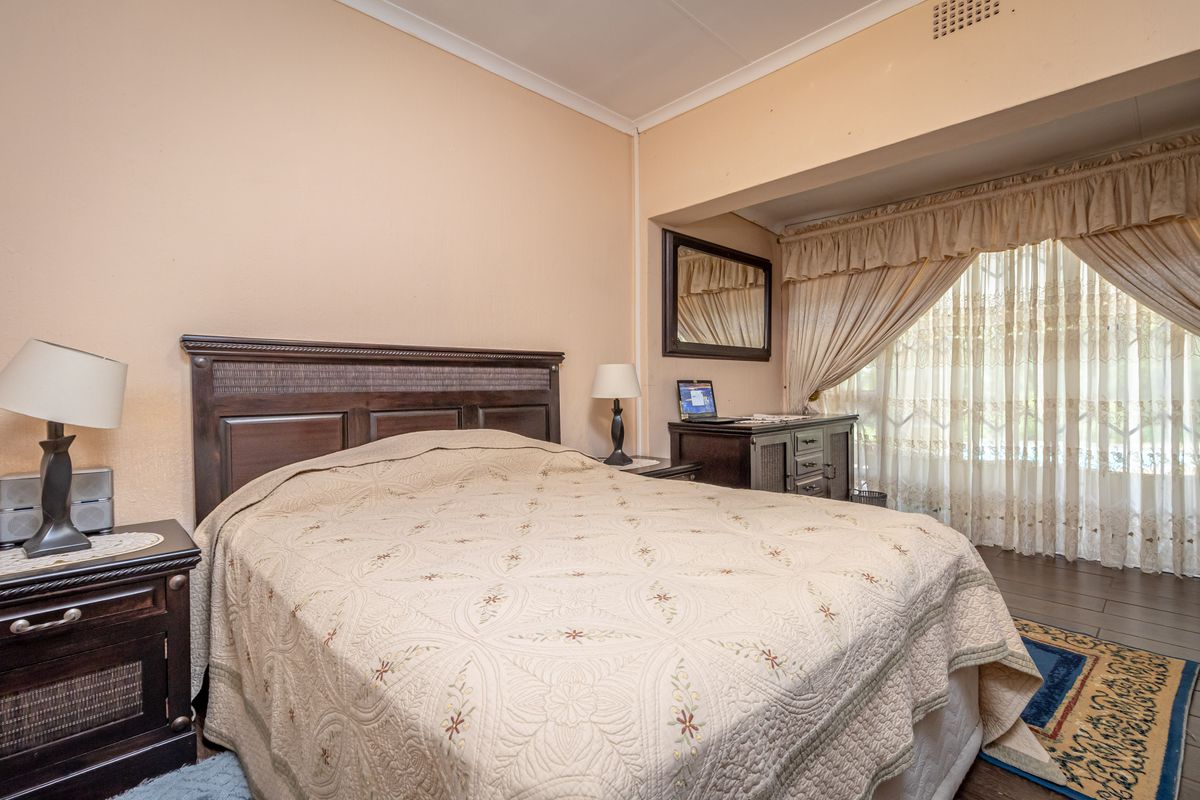 A bedroom featuring tiled flooring, a built-in curtain pelmet, and a recessed area with large windows allowing natural light.
