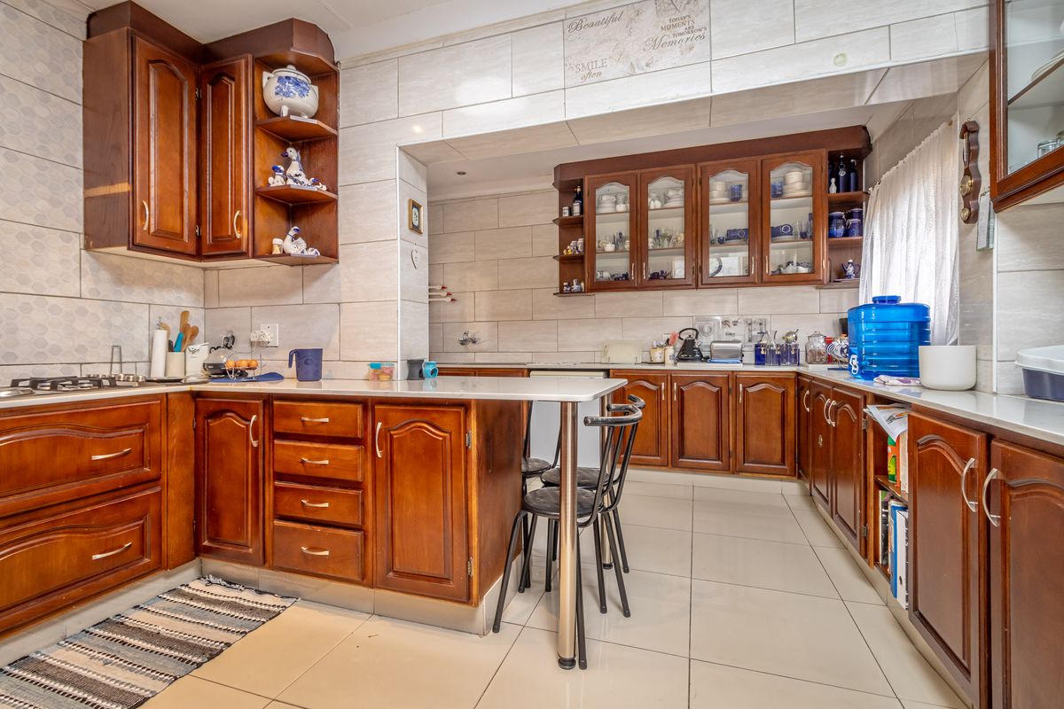 A traditional kitchen featuring dark wood cabinetry, tiled walls, and a built-in breakfast counter with integrated storage.