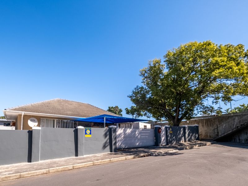 Front exterior view of the property featuring a secure perimeter wall, sliding gate, and a shade sail over the driveway area.