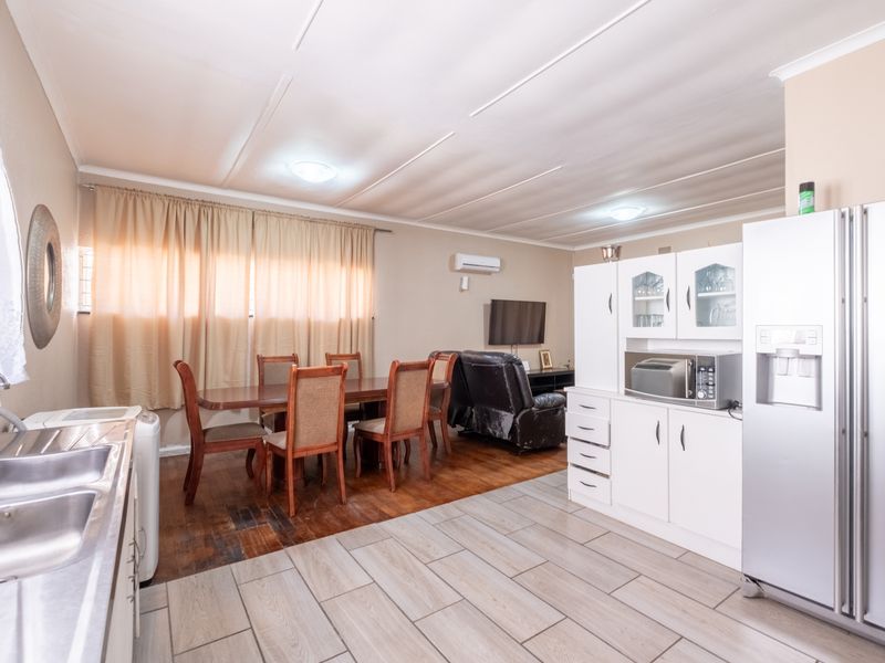 Open-plan living and kitchen area featuring a combination of tiled and timber flooring, built-in cabinetry, and a wall-mounted air conditioning unit.
