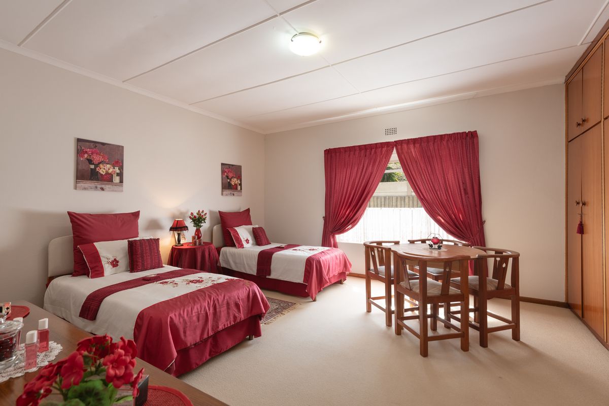 Spacious bedroom featuring built-in wooden wardrobes, neutral carpeting, and large windows with curtains, offering a comfortable and functional living space.