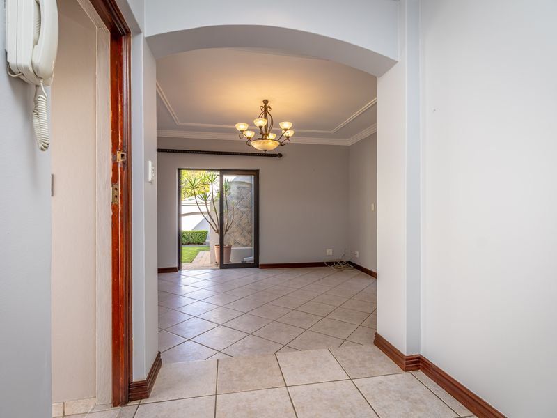 An empty living area featuring tiled floors, an arched entryway, and a sliding glass door leading to the exterior.